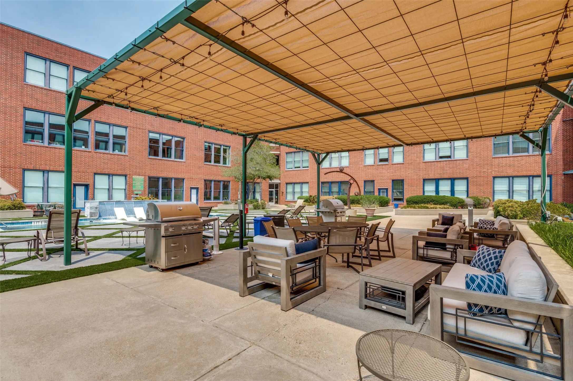 Expansive patio area featuring a shade canopy, concrete flooring, and artificial turf accents