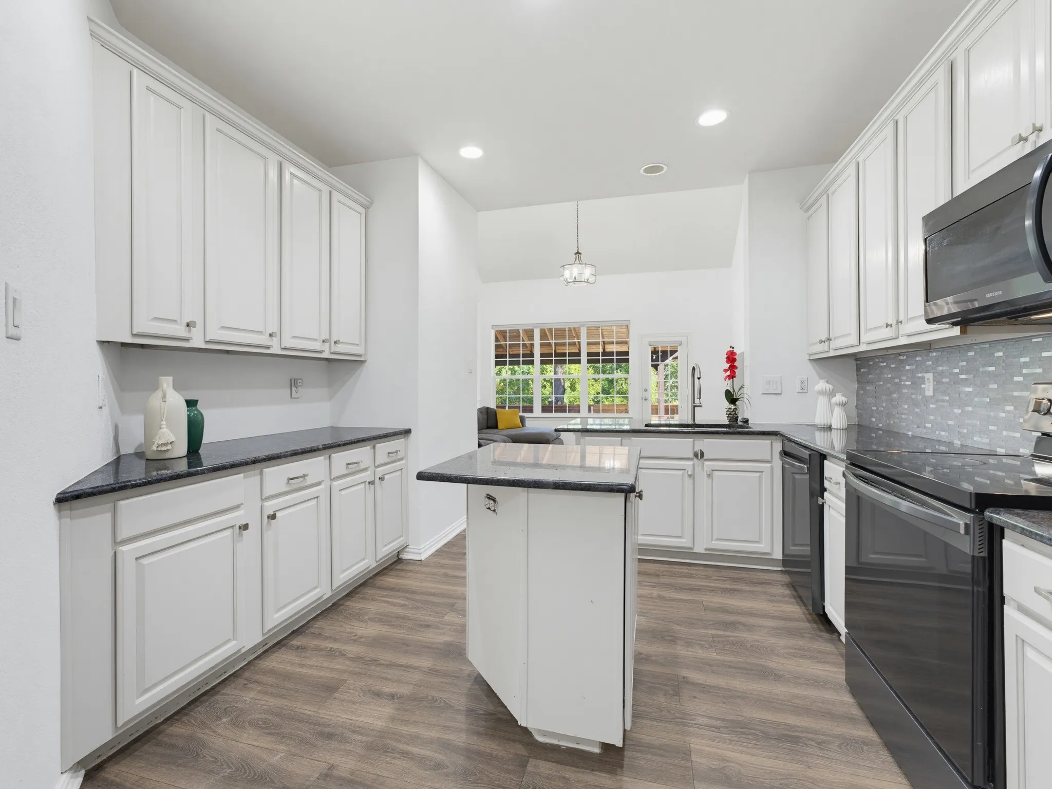 Modern kitchen featuring white cabinetry, dark countertops, wood-finish flooring, a kitchen island, and stainless steel appliances