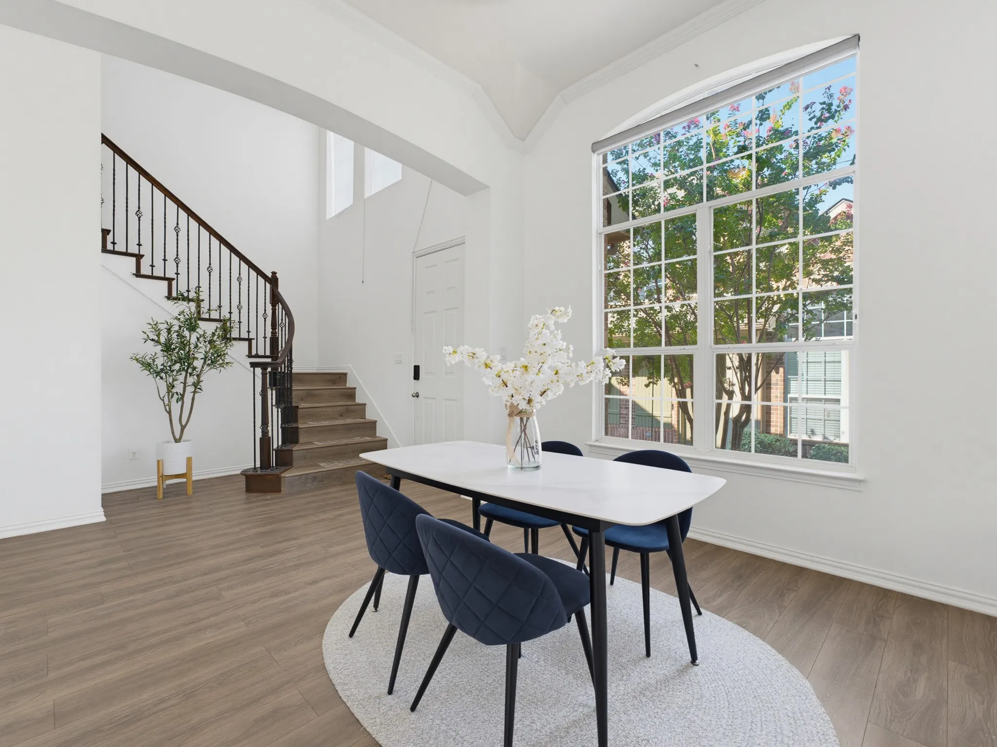 Vaulted ceilings, wood-finish flooring, a large grid-pane window, and a grand staircase with wrought iron balusters