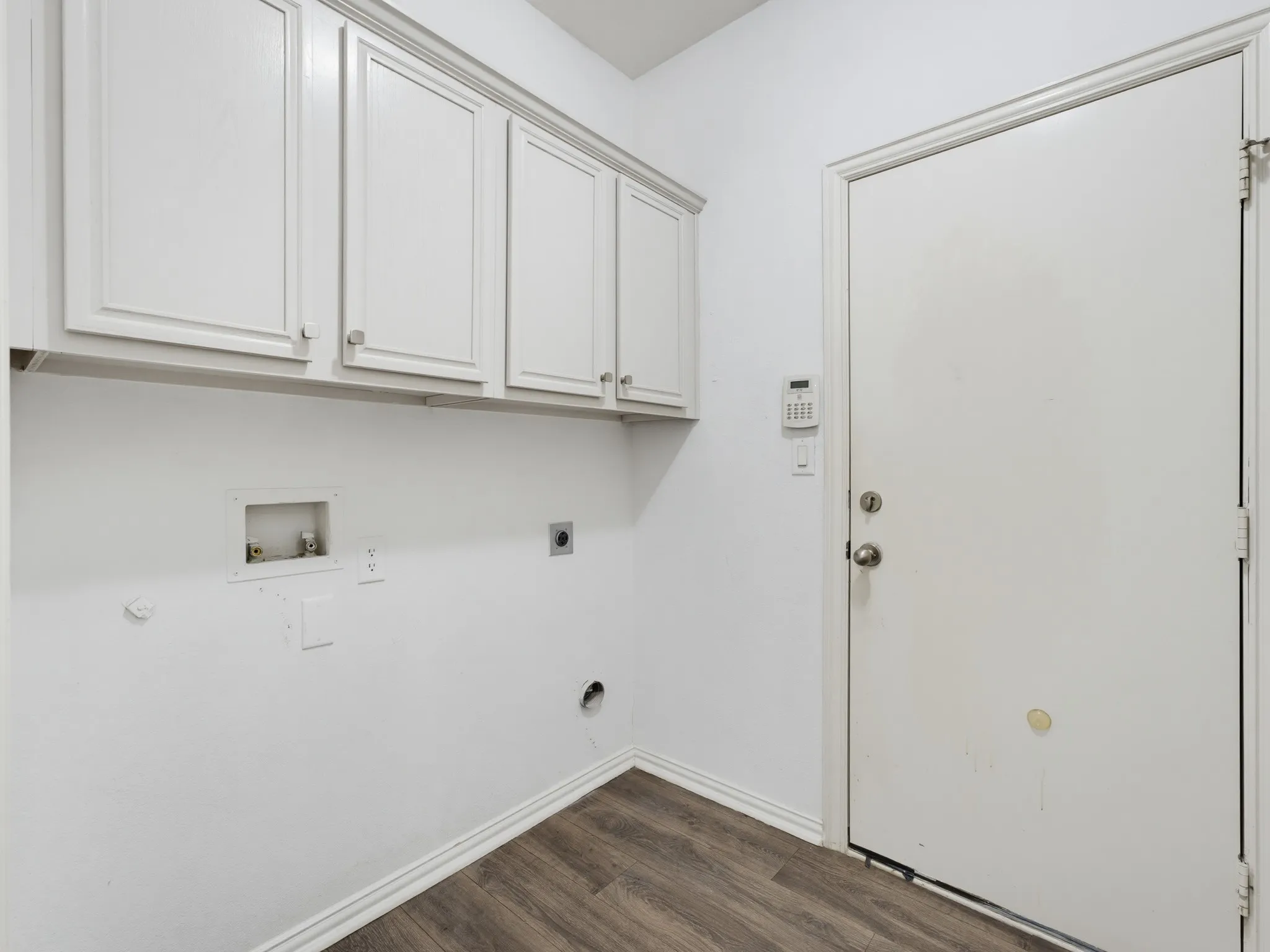 Laundry area featuring white cabinetry, wood-finish flooring, and a solid-core door