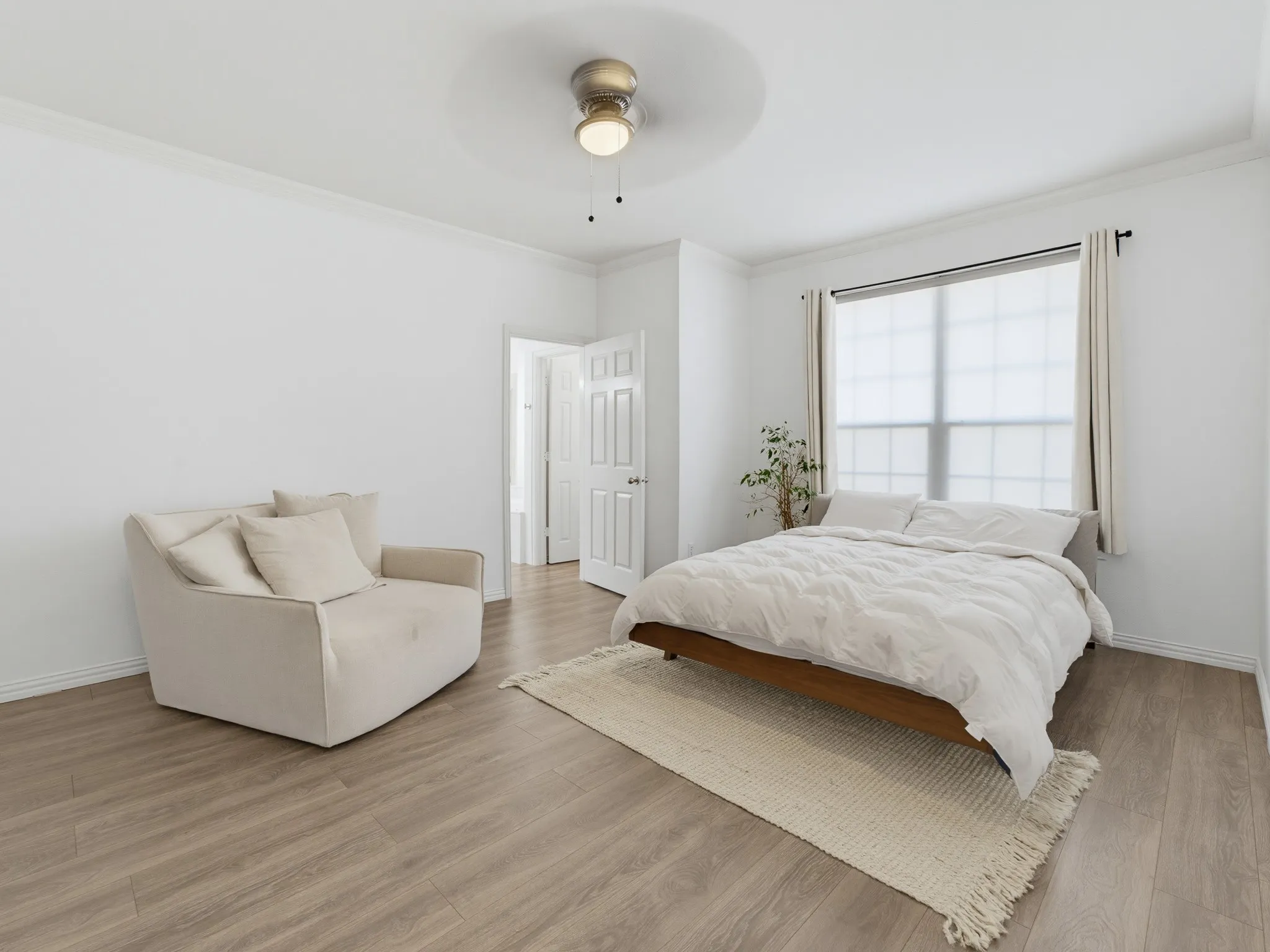 Recessed window with roller shade, wood-finish flooring, ceiling fan with integrated lighting, crown molding, and paneled interior door