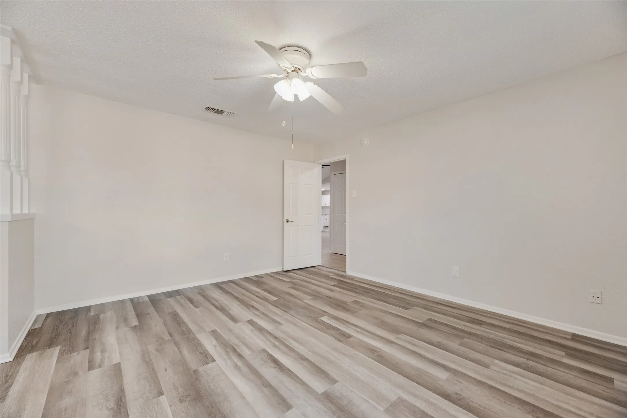 Recessed ceiling fan with light kit, wood-finish flooring, white paneled door, and white walls