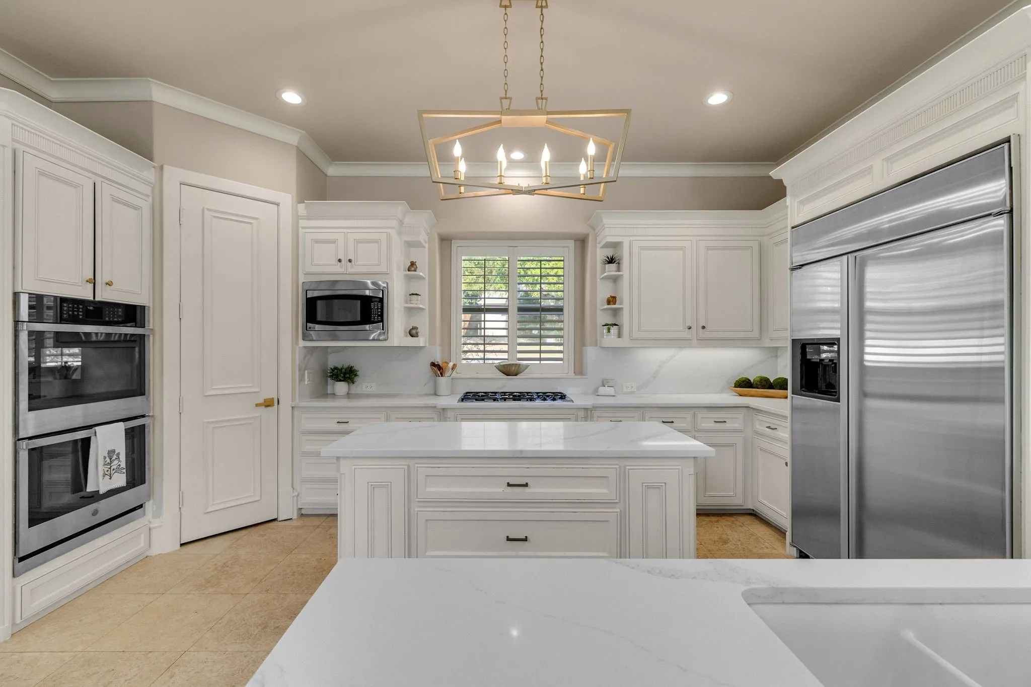 Kitchen features double wall ovens, gas cooktop, and large prep island with storage.