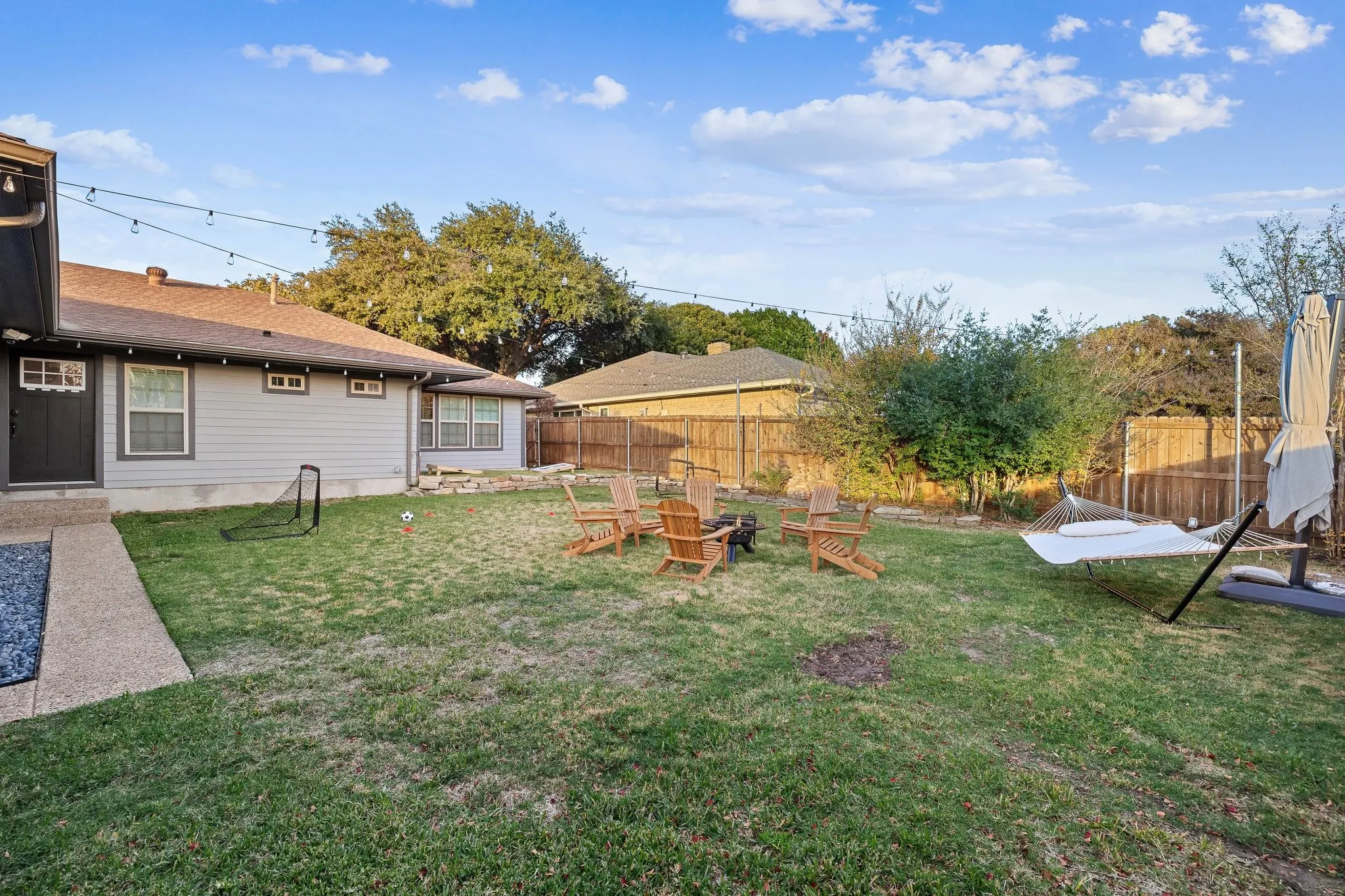 Spacious backyard with mature landscaping, established trees, and wooden fencing