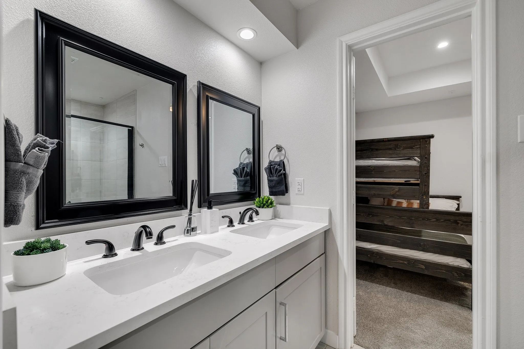 Dual-sink vanity with white quartz countertop, matte black faucetry, and framed mirrors