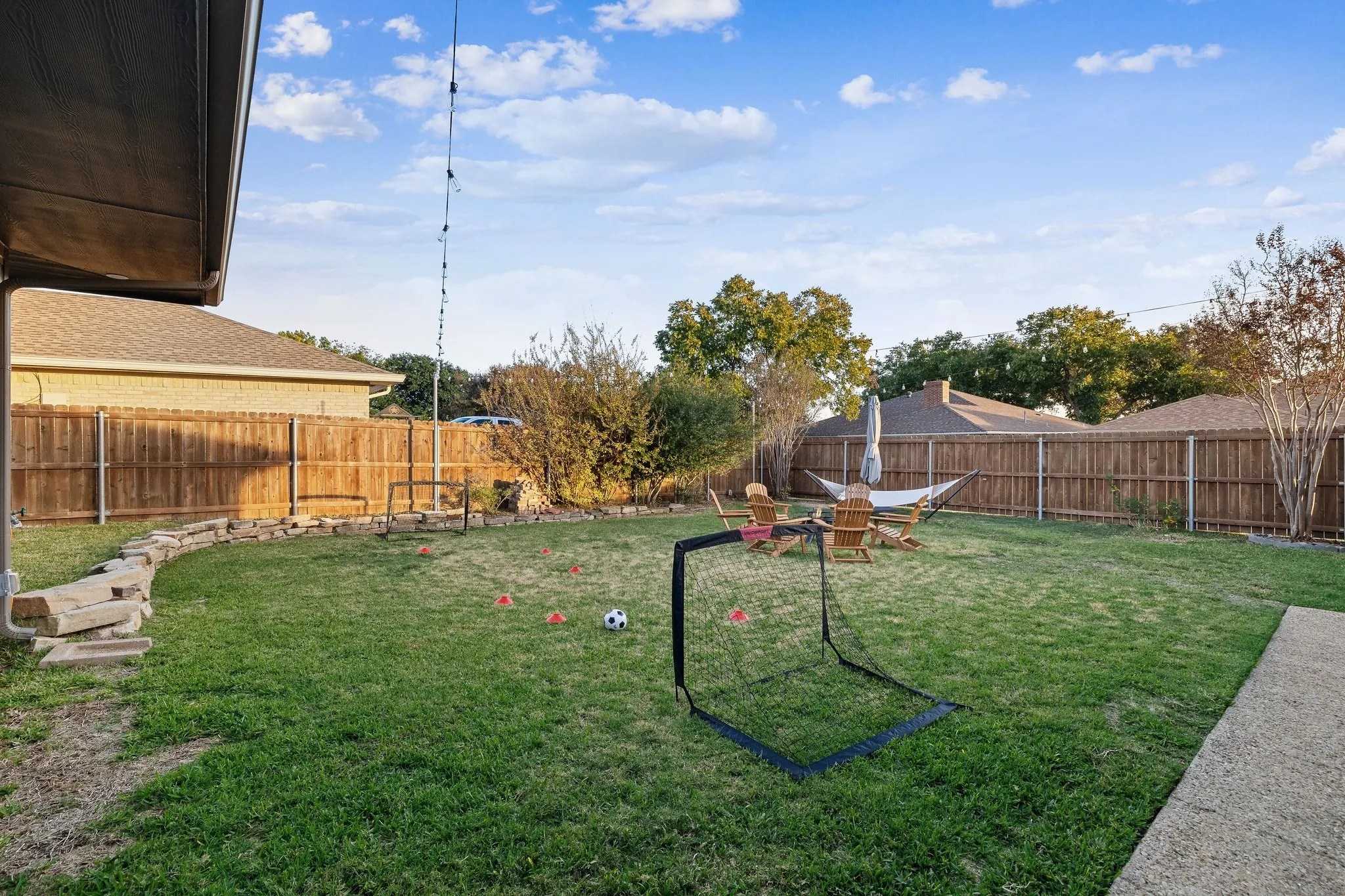 Expansive backyard featuring a manicured lawn, a full wood fence, and a curved stone landscape border