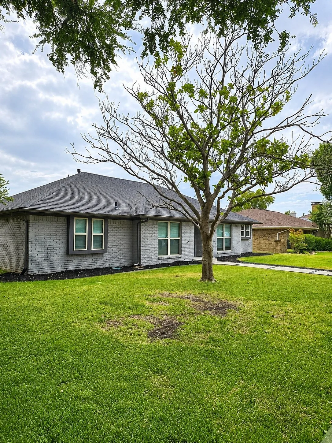 Brick exterior with painted finish, Black shingle roof, and multiple window units