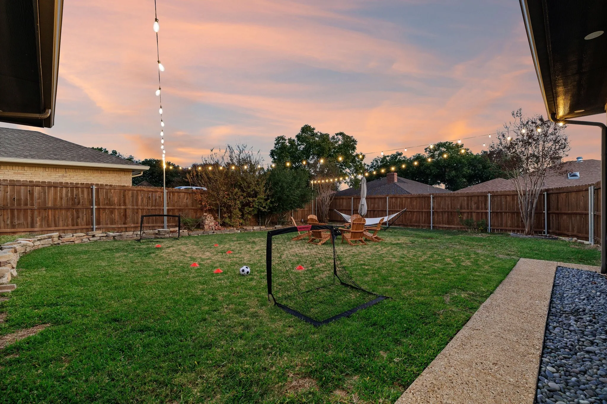 Expansive backyard oasis featuring a manicured lawn, mature landscaping, and wood privacy fencing