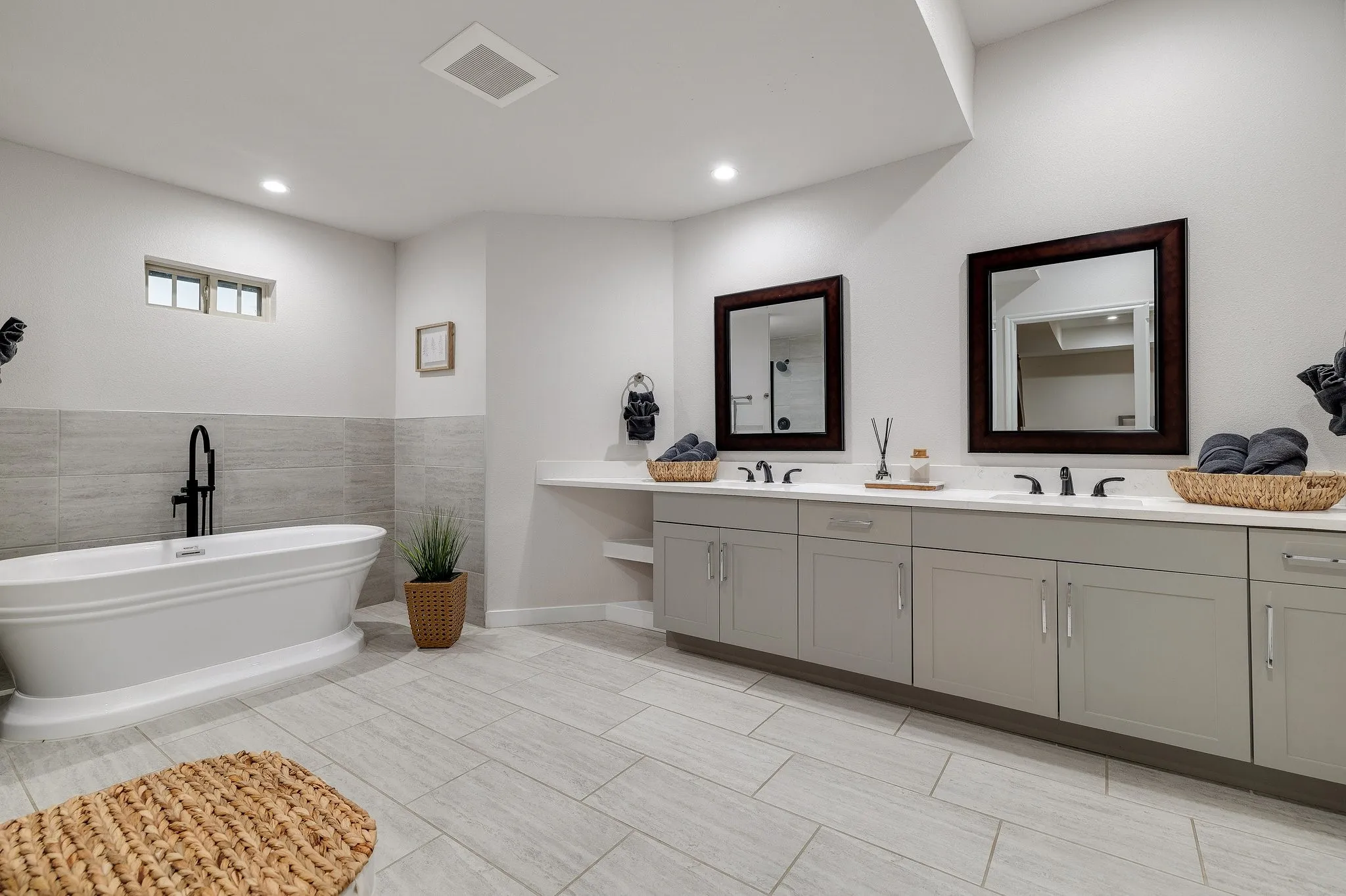 Primary bedroom suite featuring a platform bed with white bedding, carpeted flooring throughout, ceiling fan with integrated lighting, recessed ceiling lights, and a dedicated sitting area with upholstered accent chair