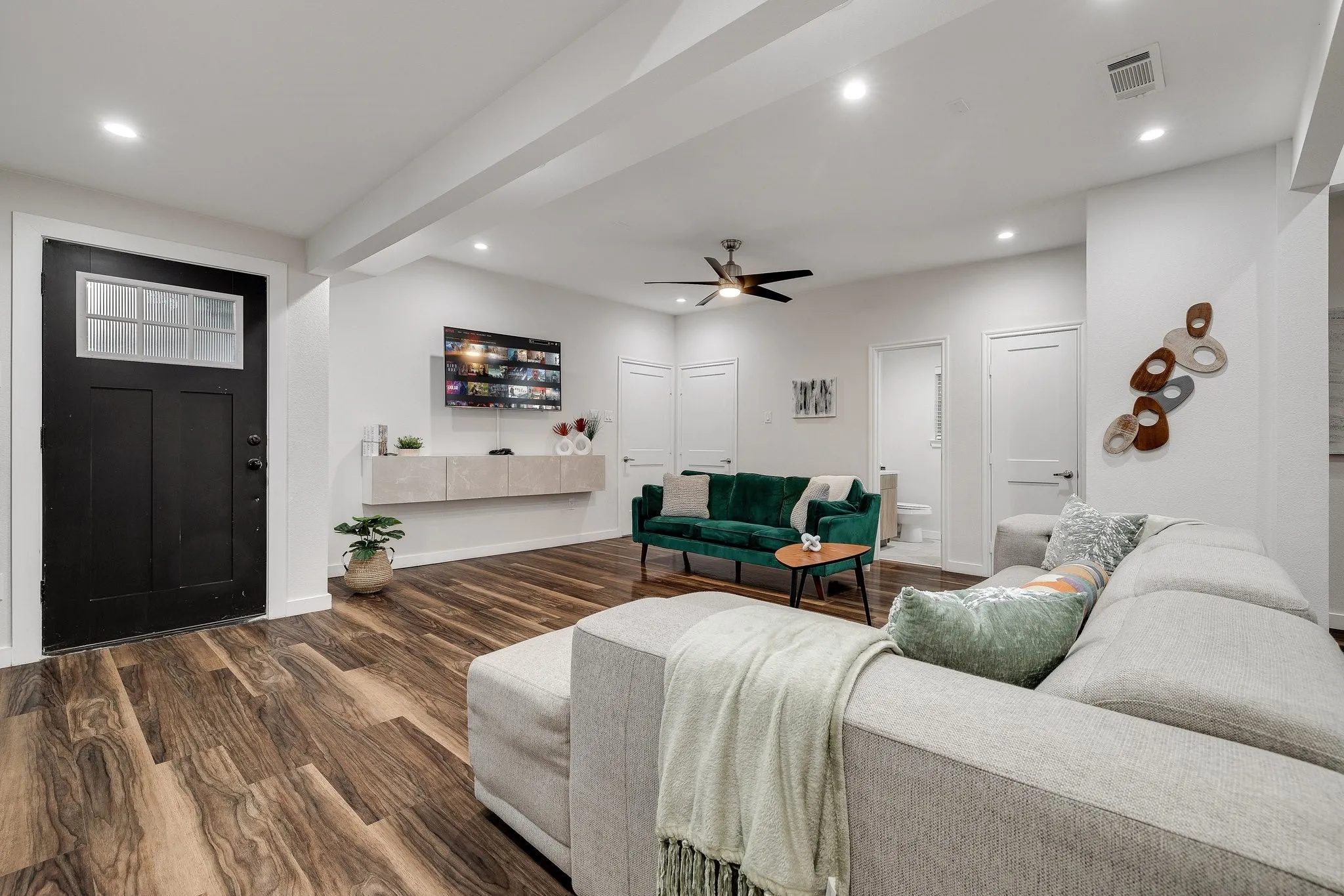Open-concept living area featuring wood-finish flooring throughout, recessed ceiling lighting, and a ceiling fan