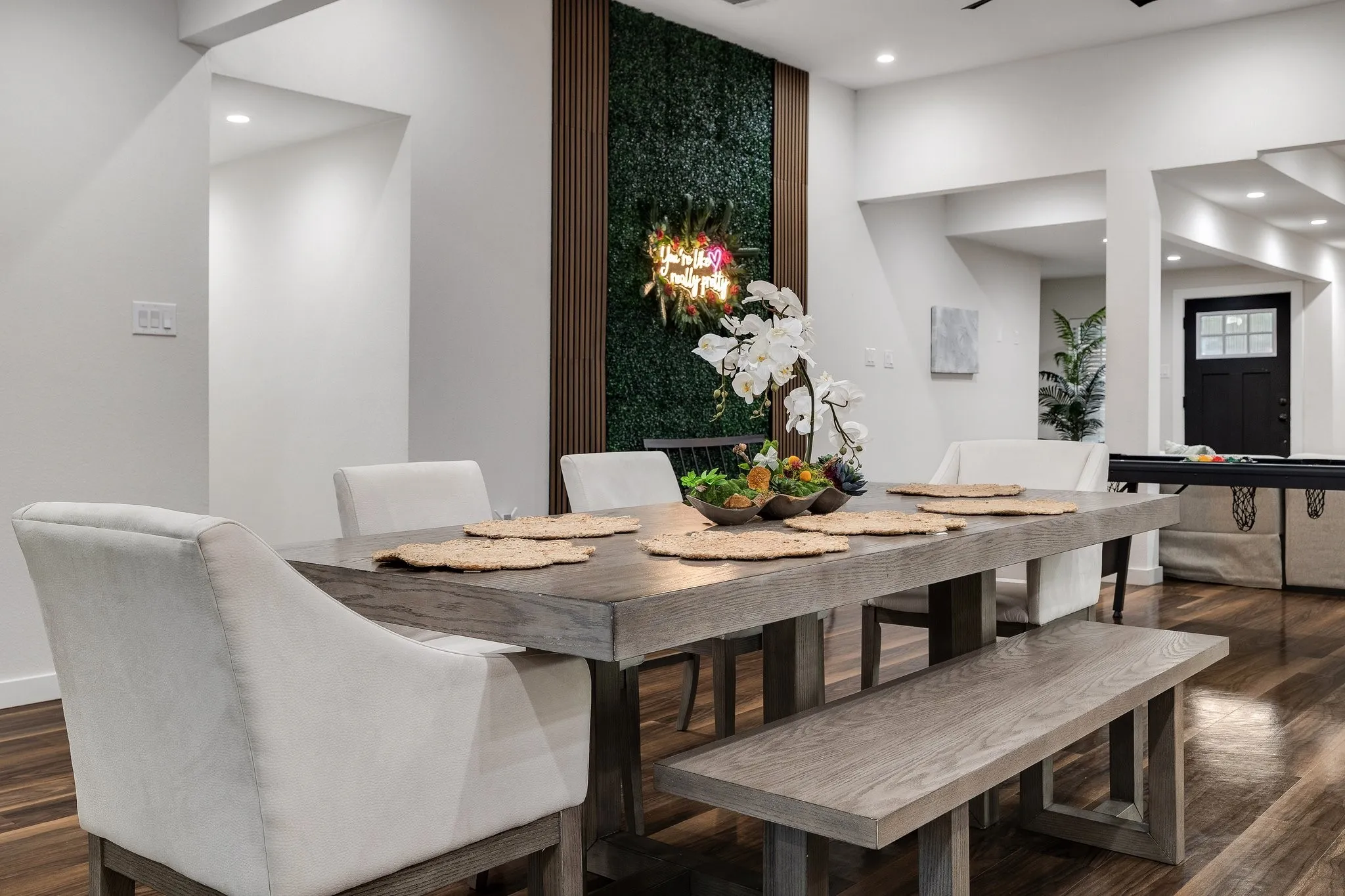 Wood-finish flooring throughout, recessed lighting, and a dark wood accent wall with integrated greenery panel