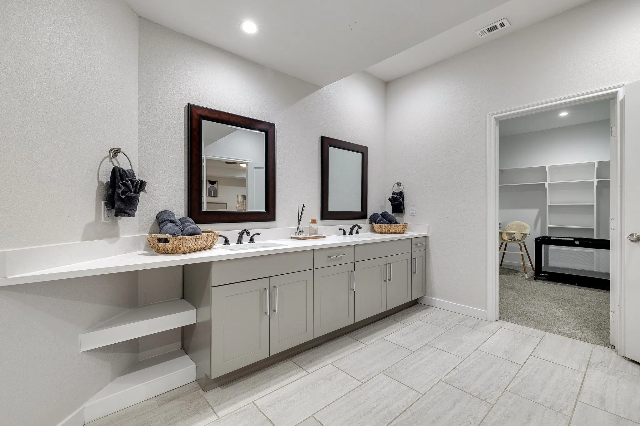 Dual vanity with integrated sinks, light gray cabinetry, and dark-framed mirrors