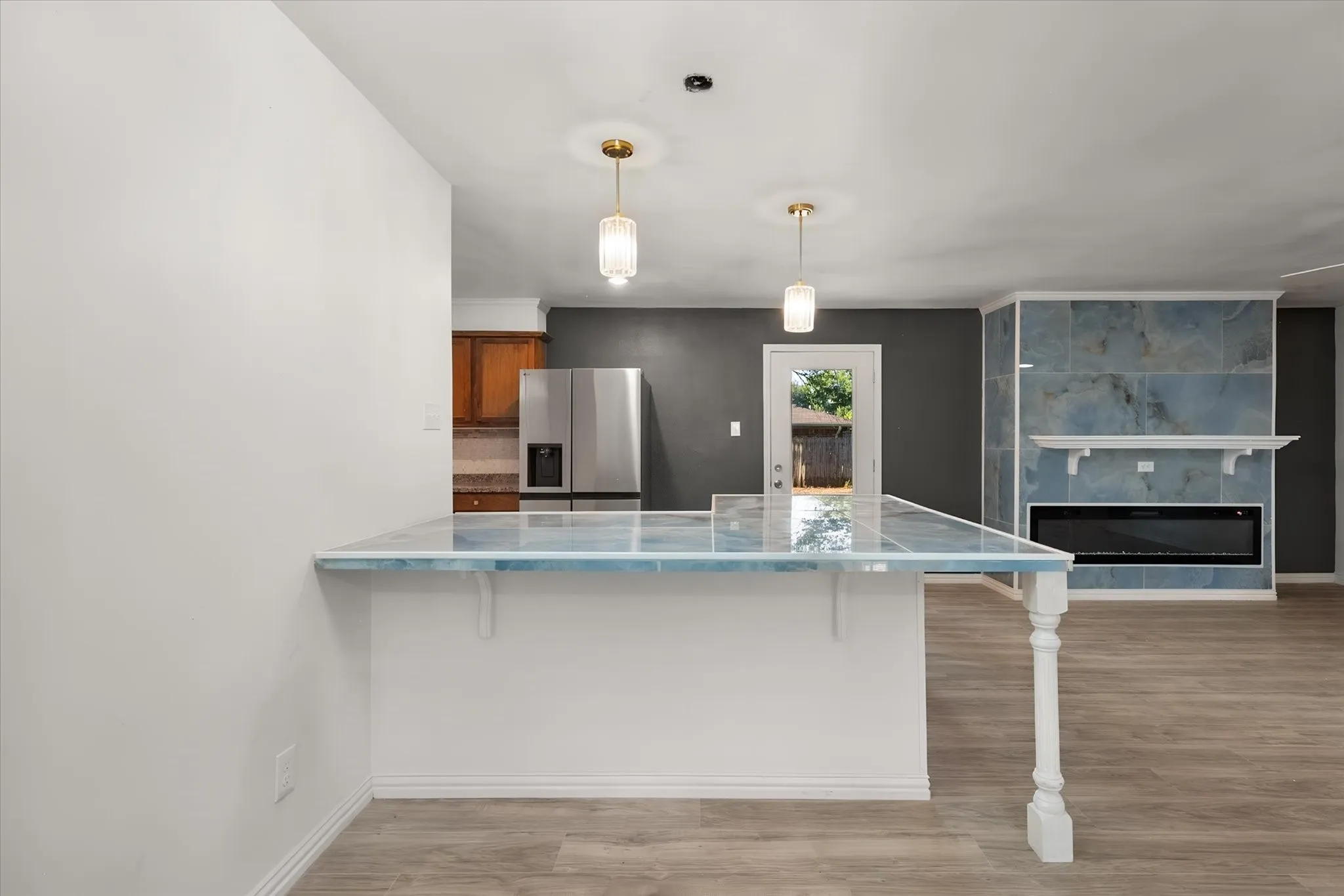 Open-concept living area featuring a breakfast bar with a tiled surface, gold-tone pendant lighting, and wood-finish flooring