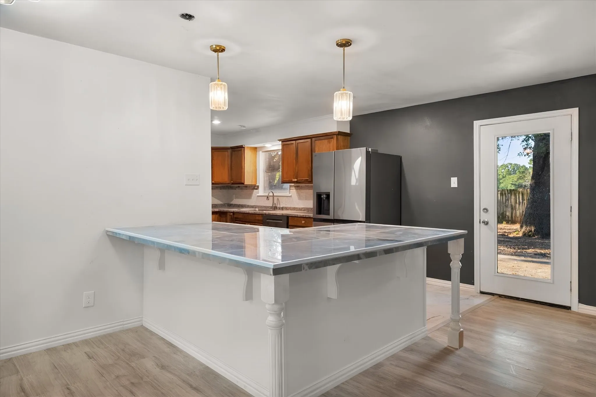 Kitchen island with a polished countertop, two pendant lights, and wood-finish flooring