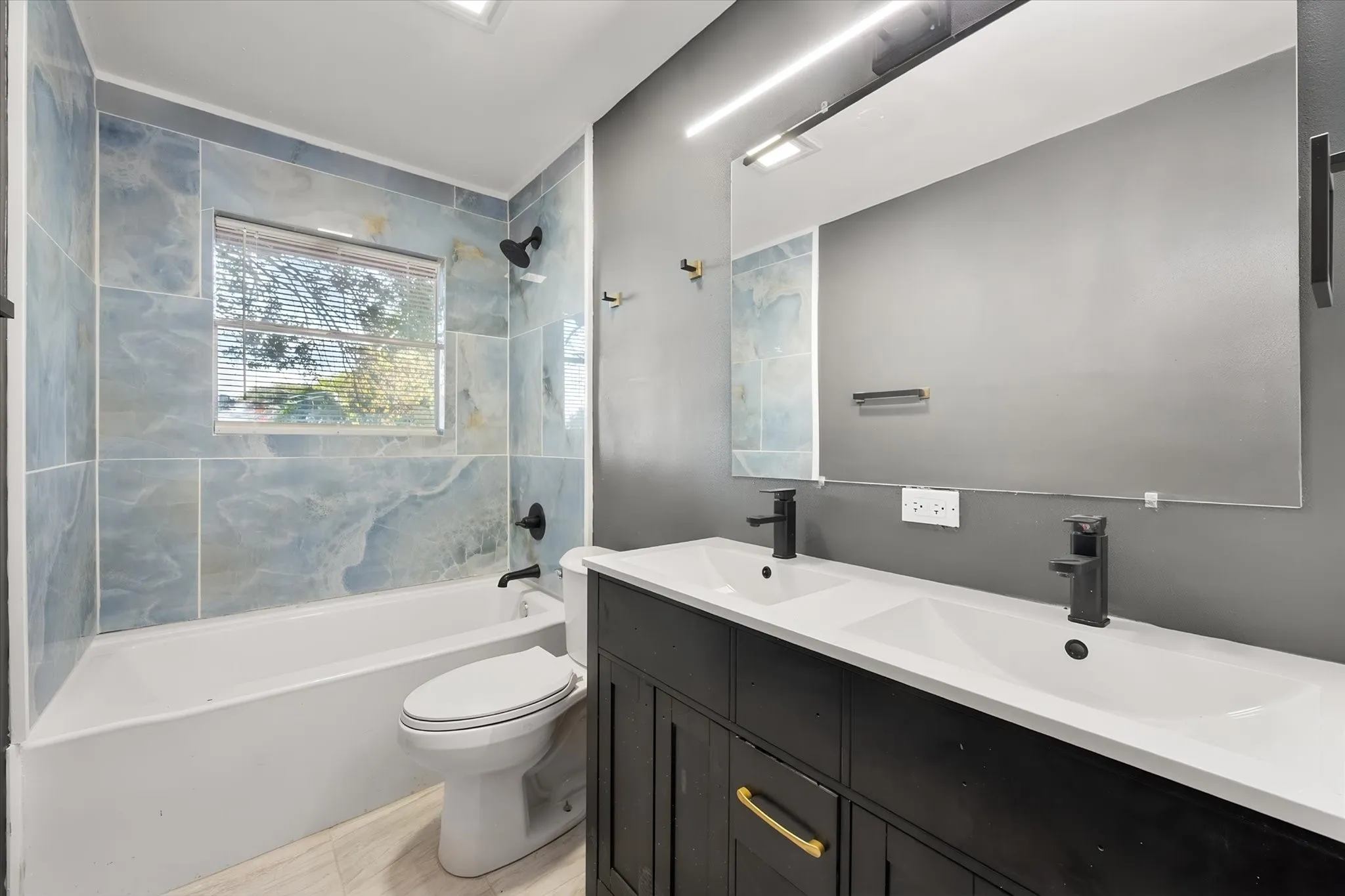 Dual vanity with integrated sinks, matte black faucets, and a dark wood-finish cabinet