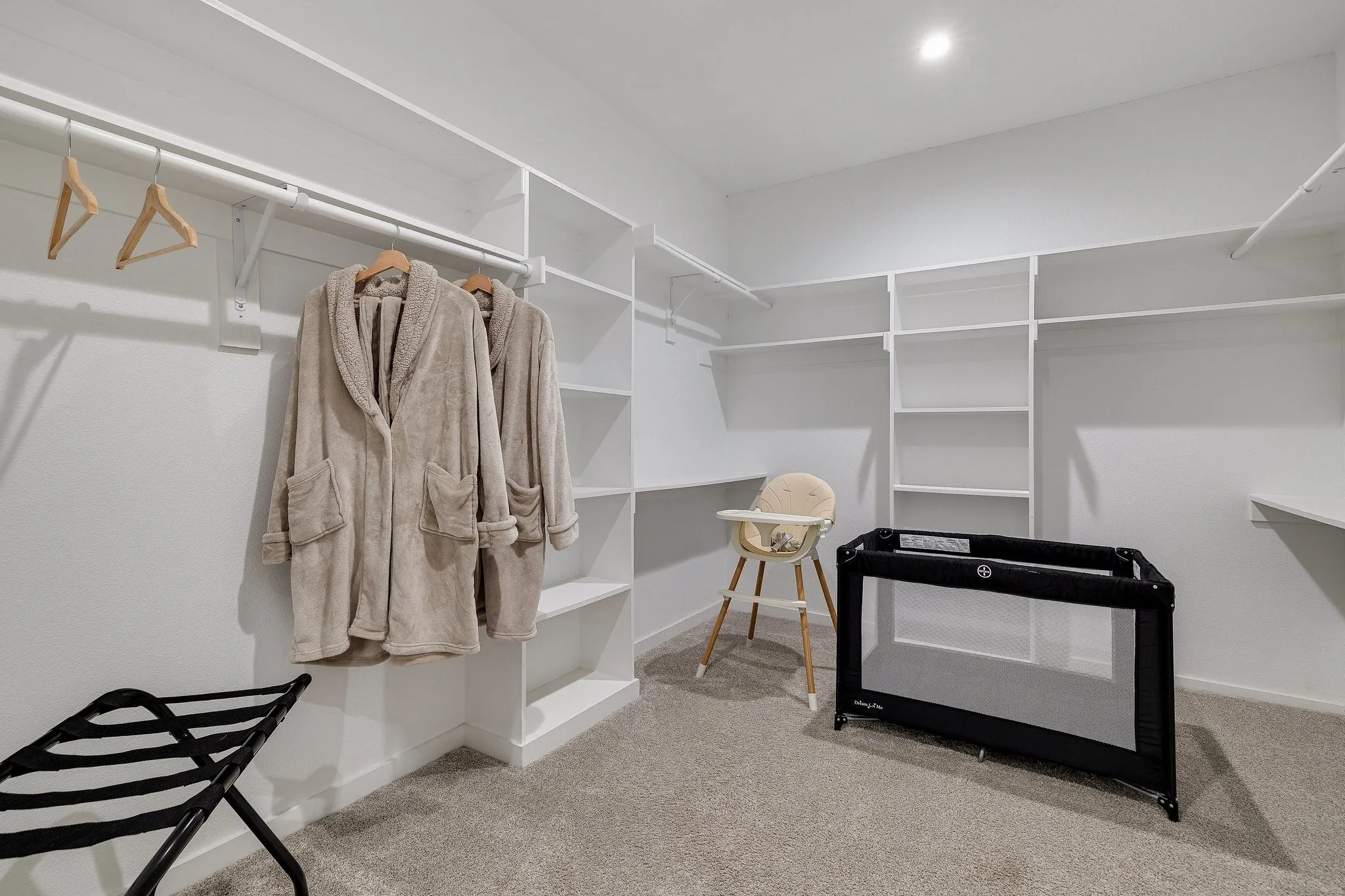 Integrated closet system featuring multiple hanging rods, extensive shelving, and carpet flooring