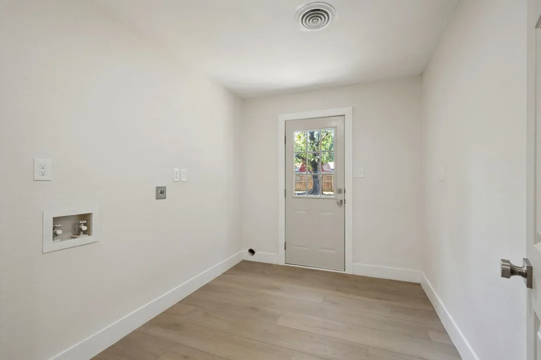 Oversized utility room with washer and dryer connections, updated flooring, exterior access, and substantially more room for storage and organization than a typical laundry closet.