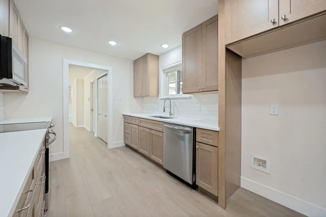 Renovated kitchen featuring shaker-style cabinetry, quartz countertops, subway tile backsplash, stainless-steel dishwasher and microwave, single-basin sink, recessed lighting, and generous storage.