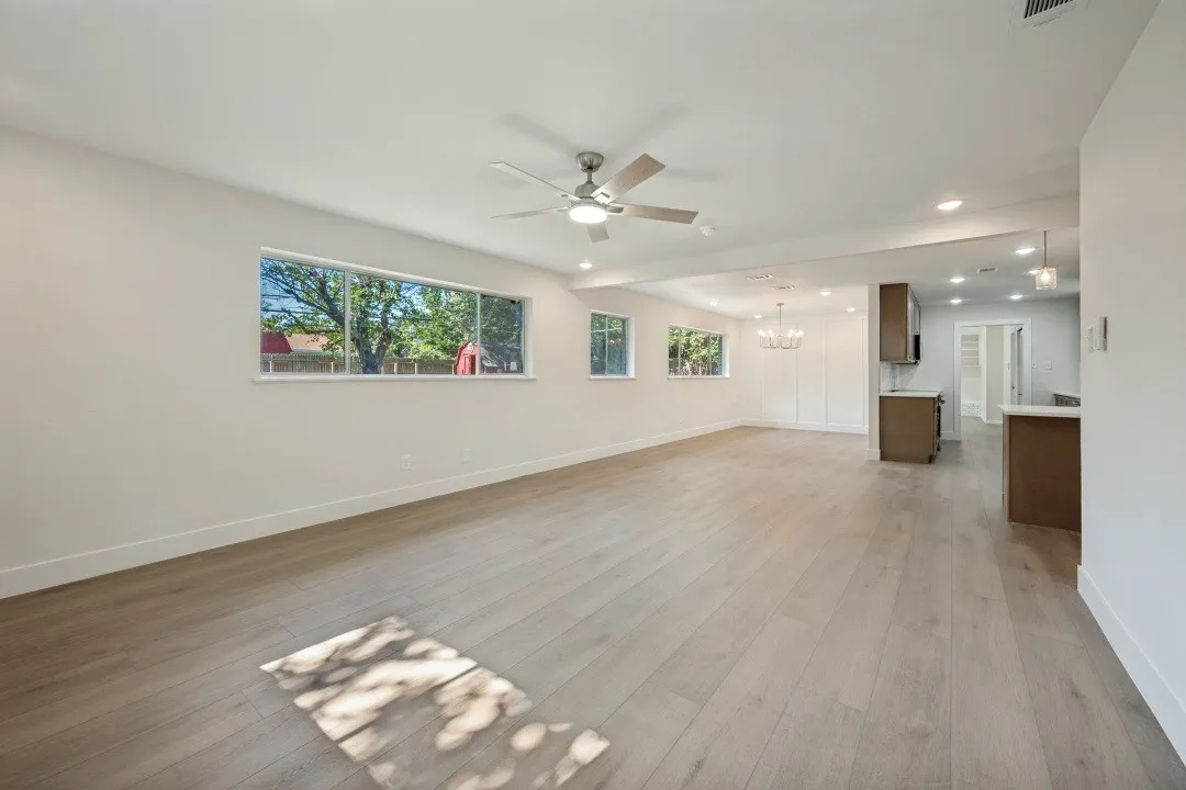 Expansive main living space with luxury vinyl plank flooring, multiple windows, recessed lighting, contemporary ceiling fan, and an open sightline toward the dining area and kitchen.