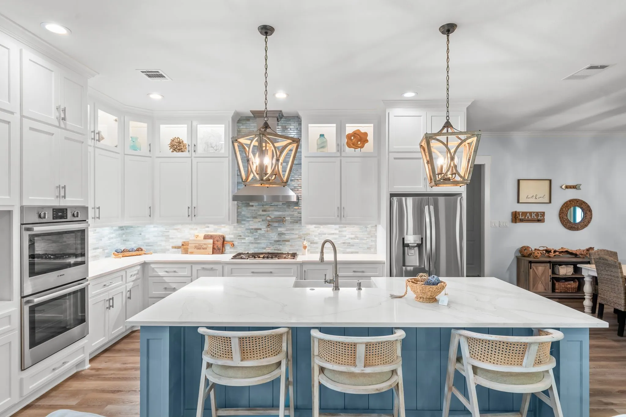 Luxury modern farmhouse kitchen features an oversized island, quartz countertops, farmhouse sink, double ovens, and abundant white cabinetry.