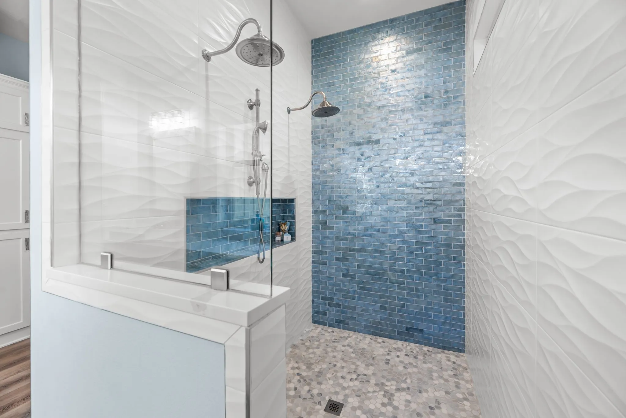 Oversized walk-in shower features beautiful tilework, glass enclosure, multiple shower fixtures, and a striking blue accent wall.