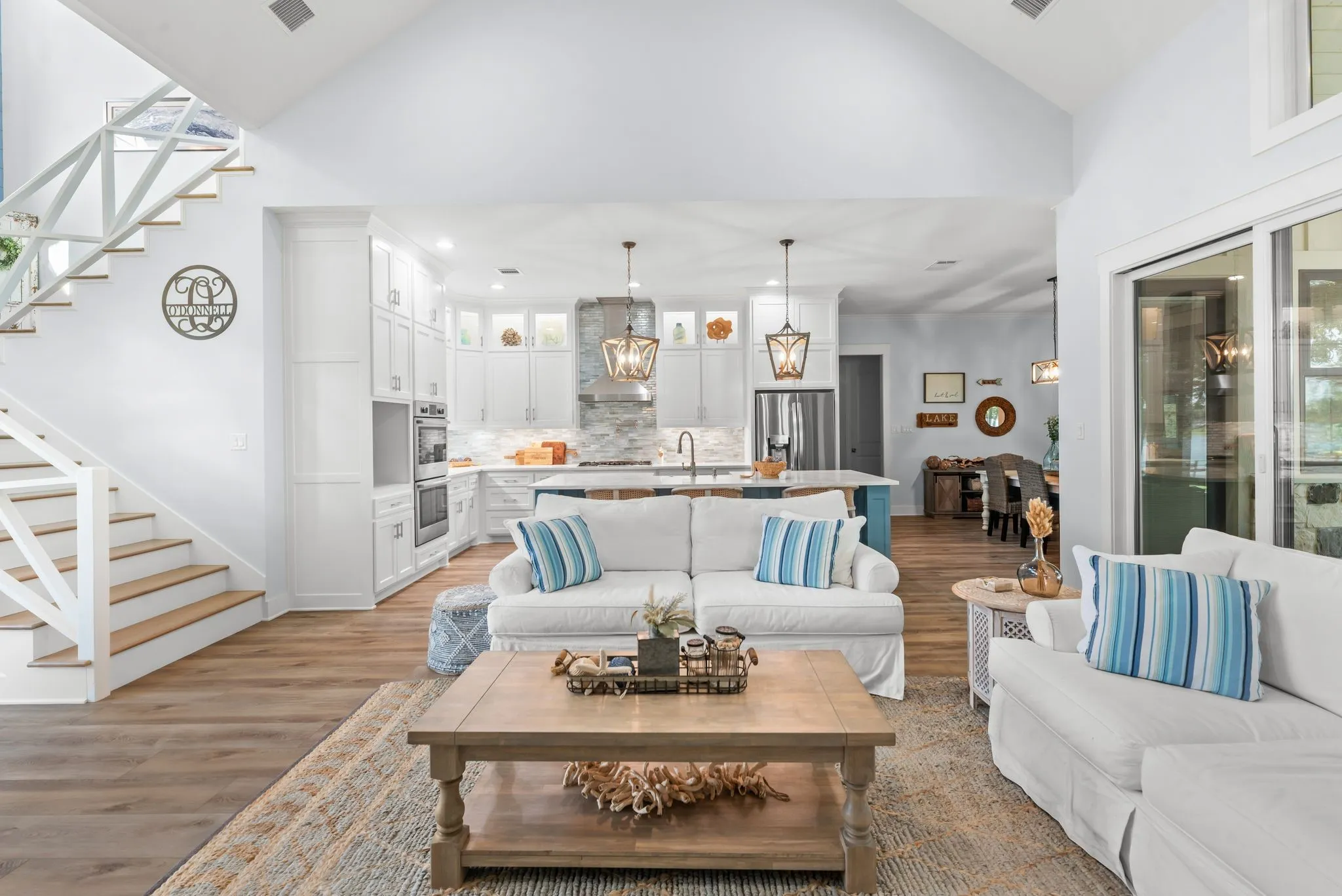 Spacious lake house living room offers abundant natural light, comfortable gathering space, and an open connection to the kitchen and dining areas.