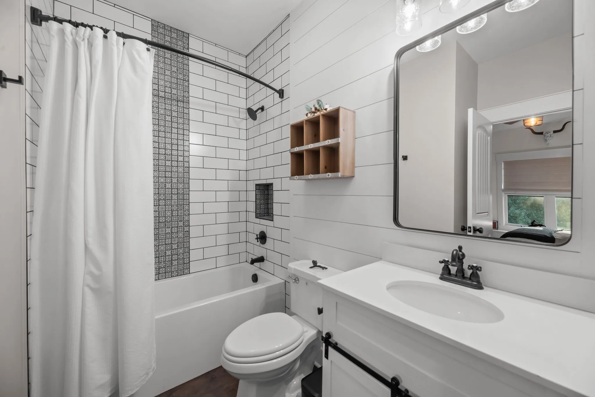 Stylish guest bathroom offers a tub and shower combination, modern vanity, and attractive black-and-white finishes.