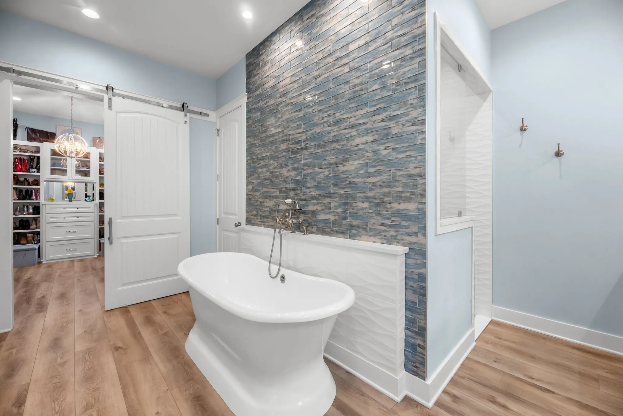 Spa-inspired primary bathroom features a freestanding soaking tub, dramatic stone accent wall, and sophisticated finishes.