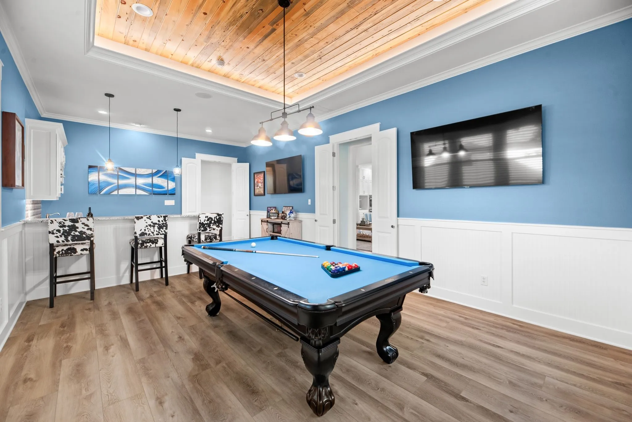 Custom game room features a pool table, wet bar, built-in cabinetry, television area, and distinctive reclaimed wood ceiling.
