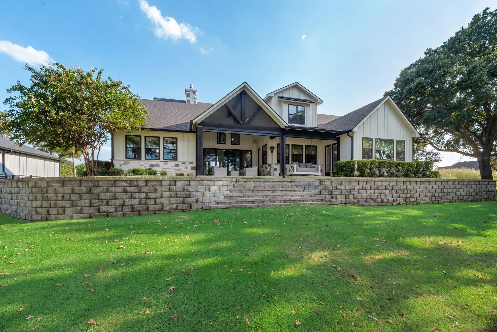 Beautiful rear exterior showcases the modern farmhouse design, mature landscaping, and spacious lawn leading toward Richland Chambers Lake.