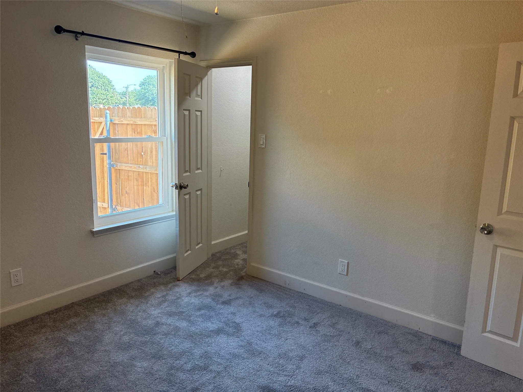 Neutral wall color, gray carpeting, a single window, and white trim