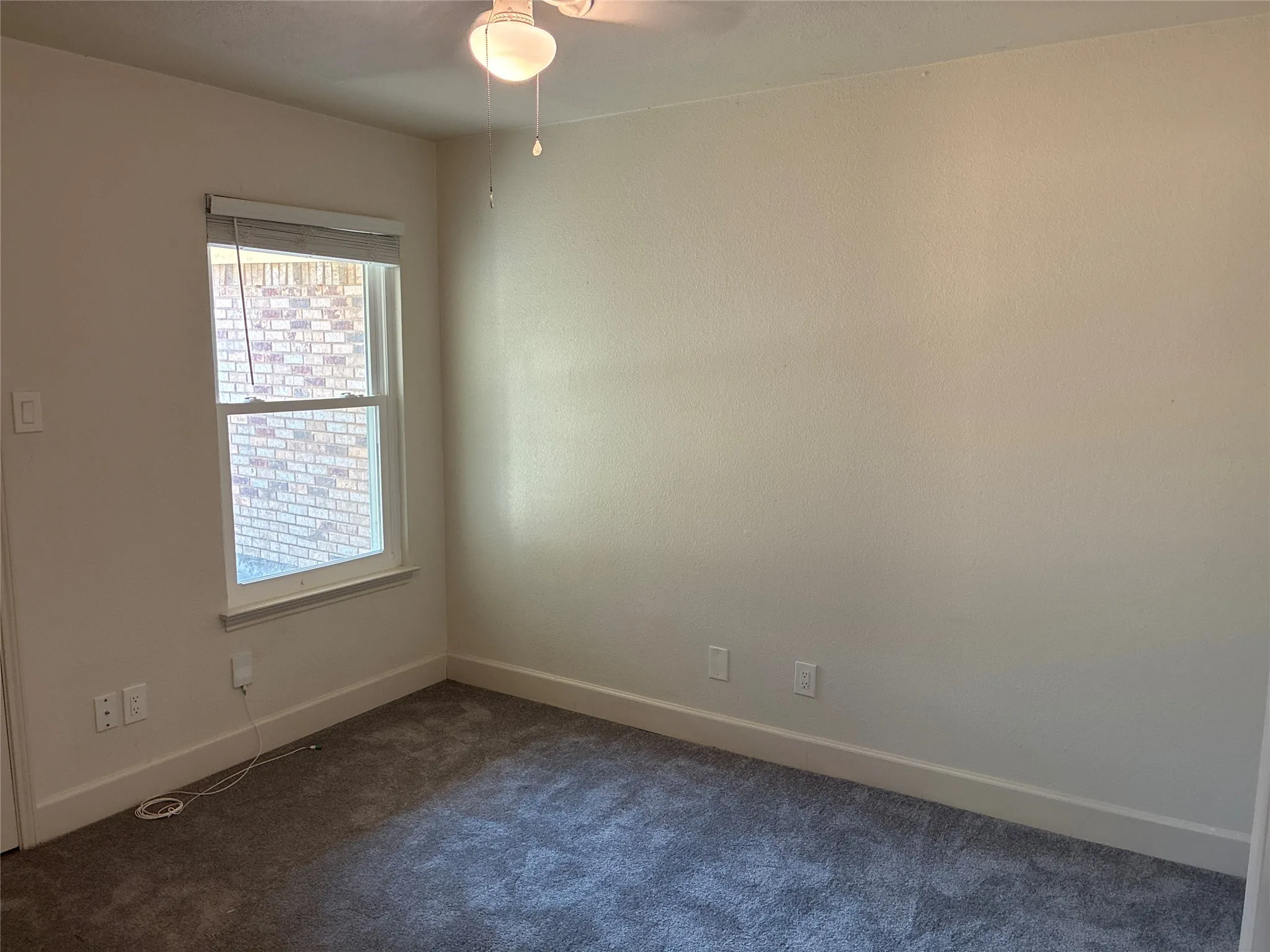 Neutral wall paint, single window, overhead light fixture, light gray carpet, and white trim