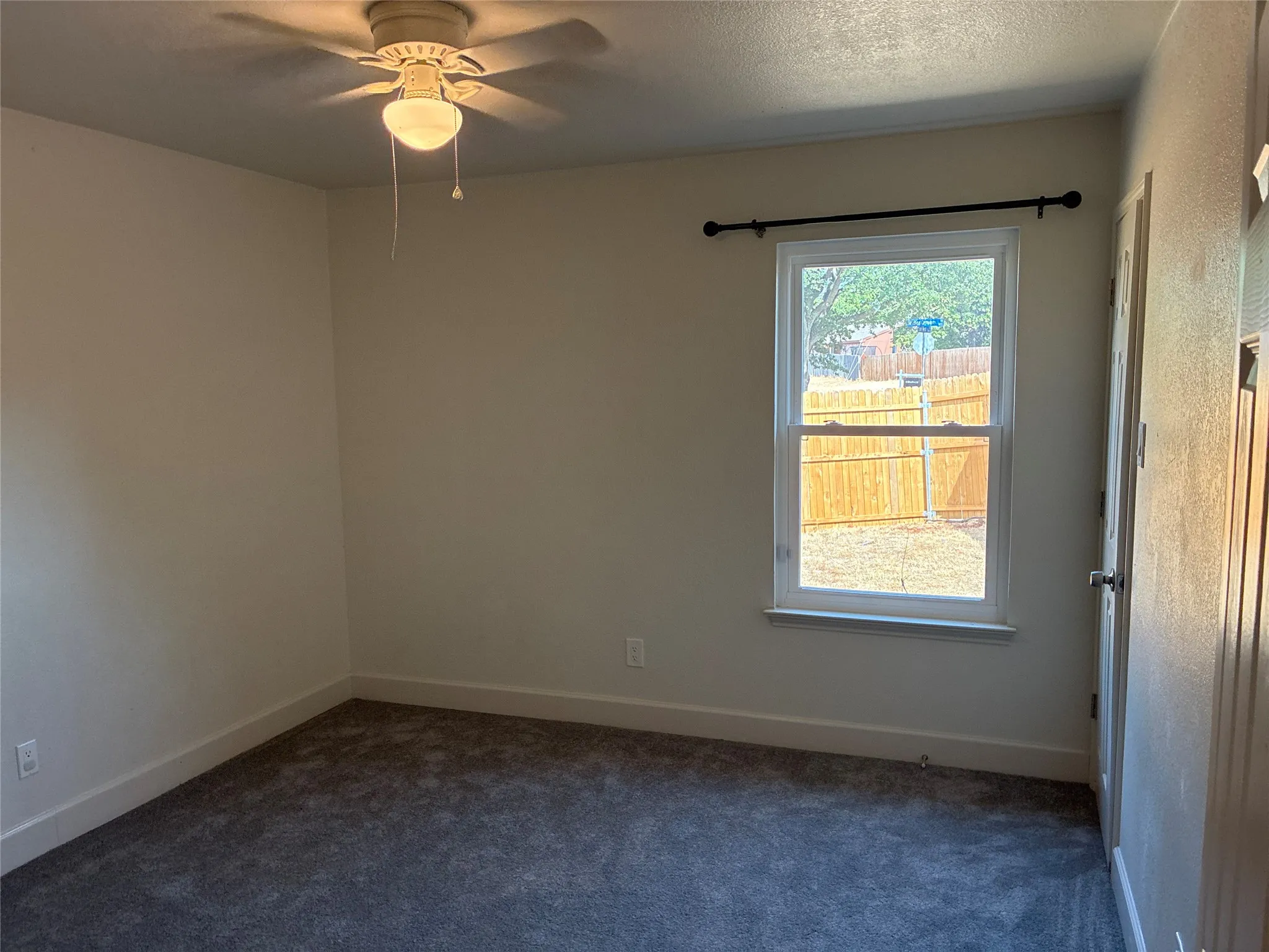 Neutral wall tones, carpet flooring, a ceiling fan, a window, and a door
