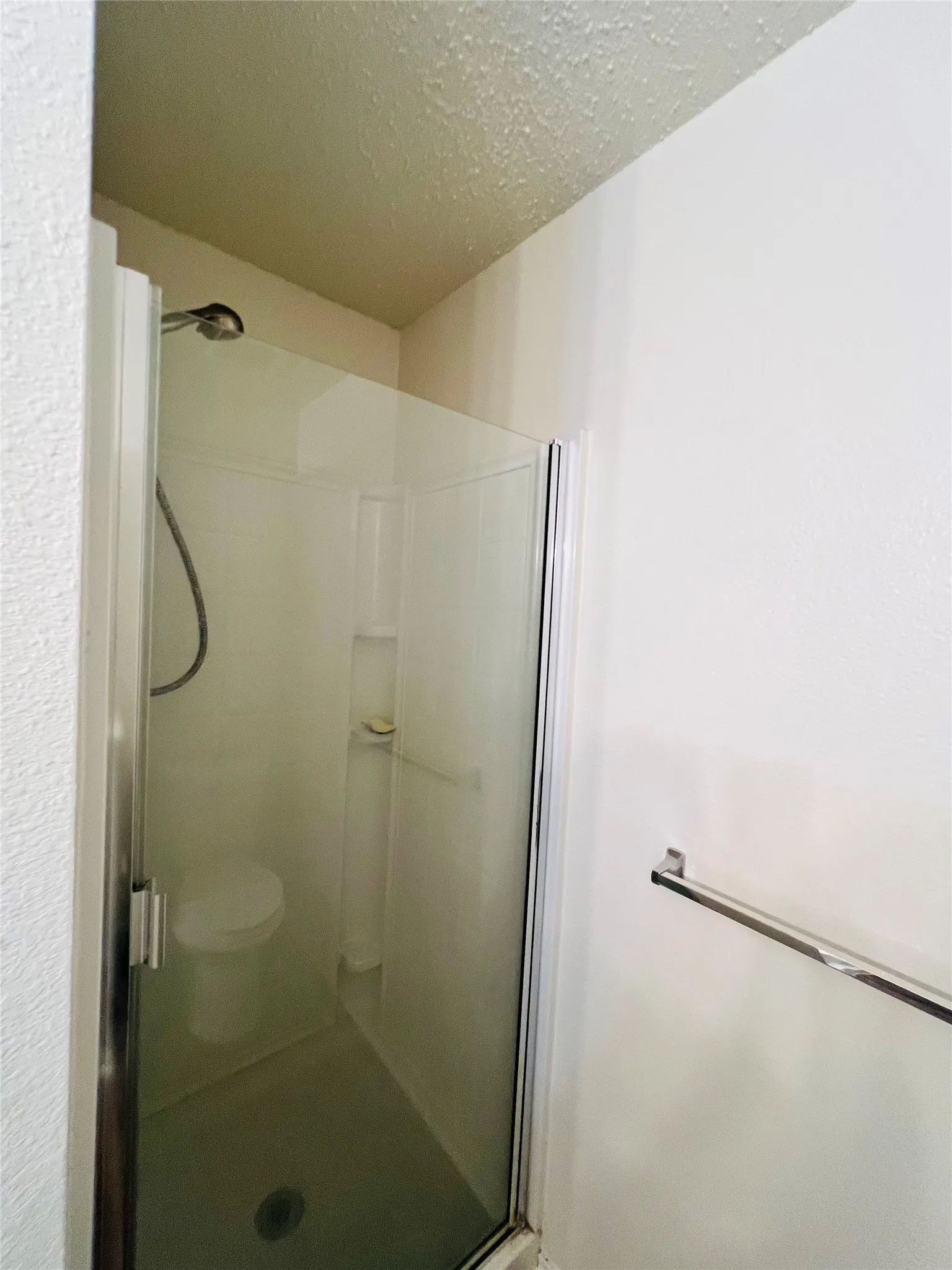 Shower enclosure with clear glass door, chrome hardware, and a wall-mounted shower head