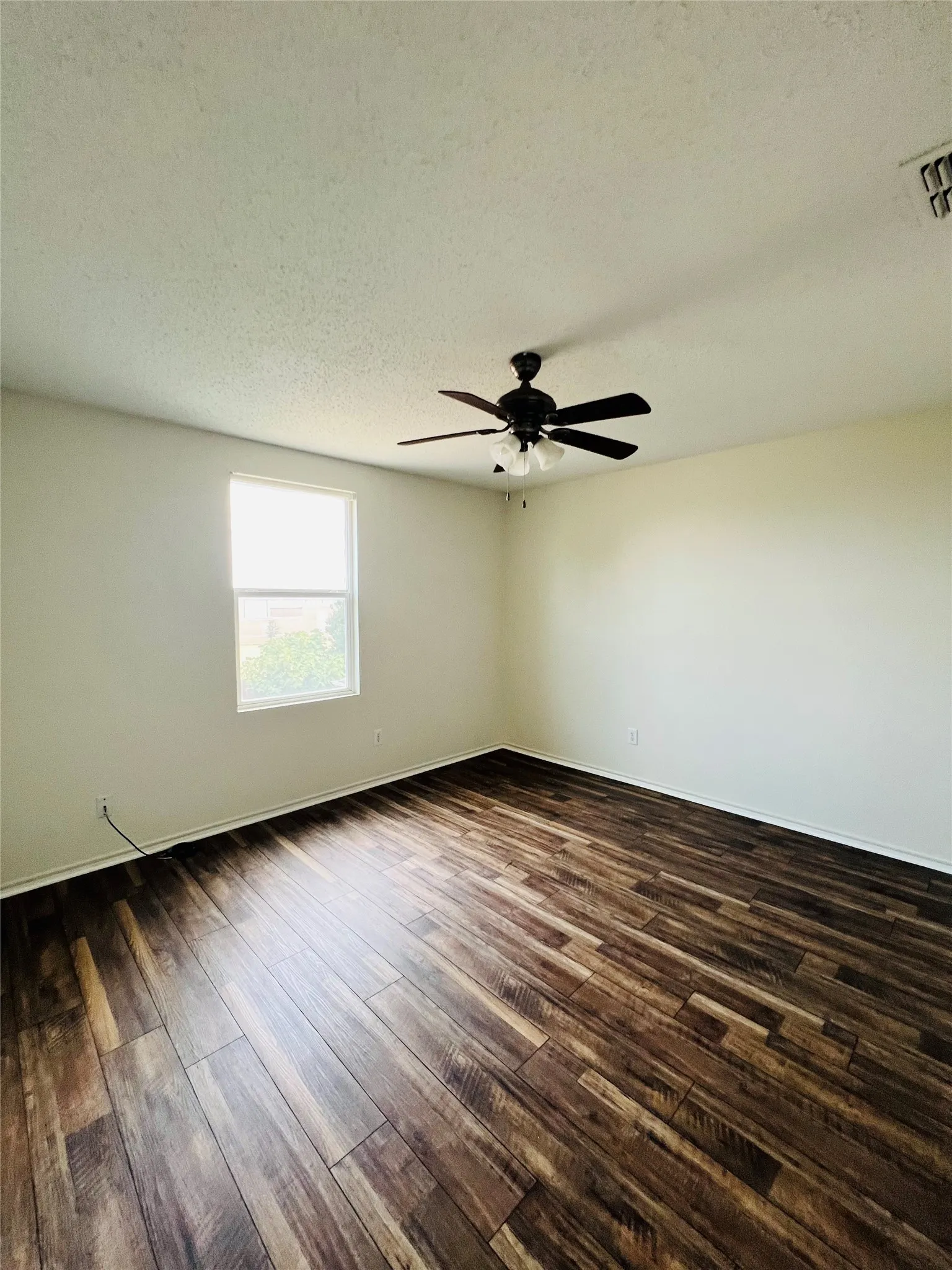 Wood-finish flooring, white wall paint, single window, and a ceiling fan with integrated lighting