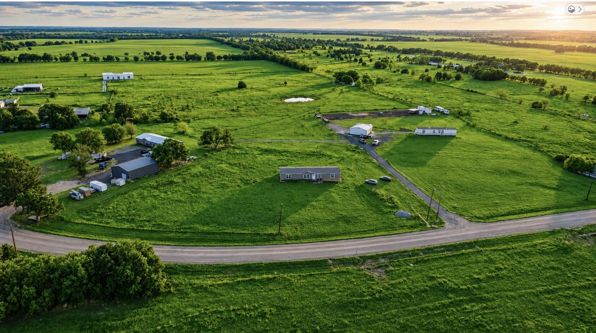 Expansive green landscape with scattered structures and a winding road