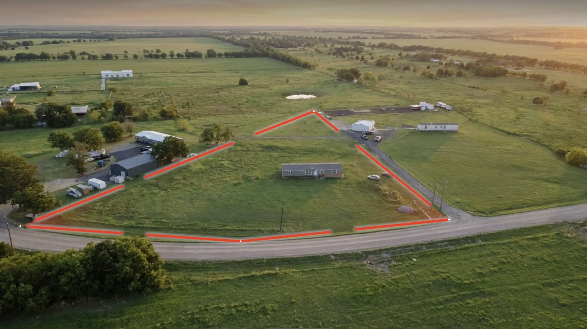 Extensive lot featuring multiple structures, open green spaces, and direct road frontage