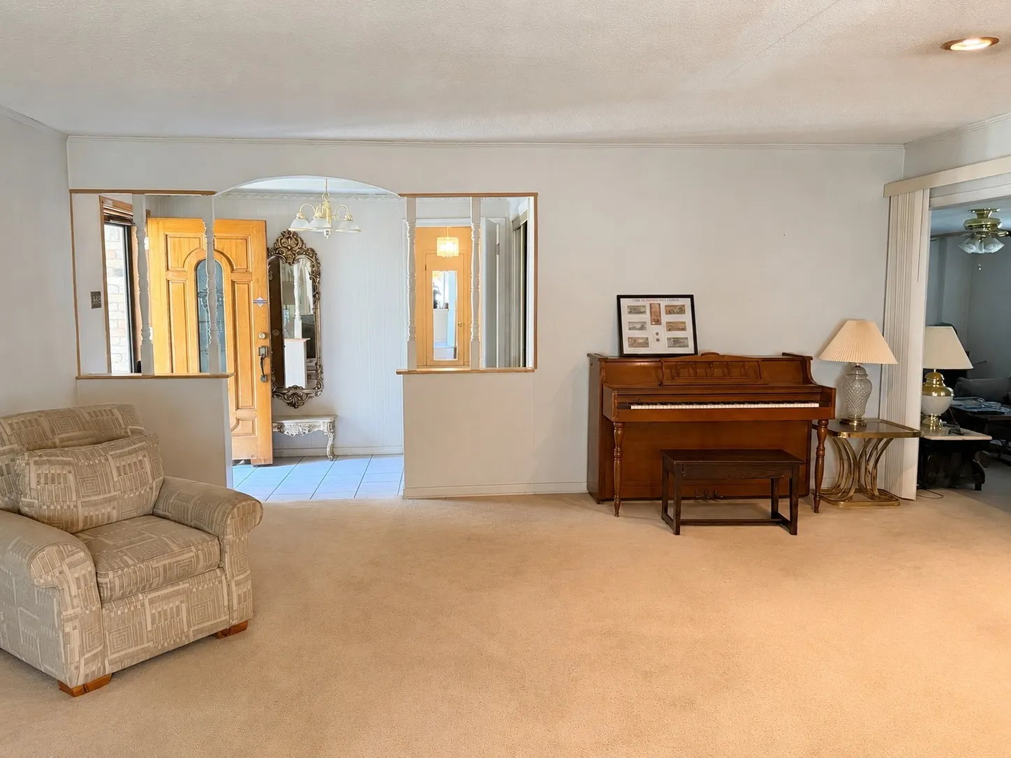 Carpeted flooring, arched doorway with wood trim, and a wood-paneled door