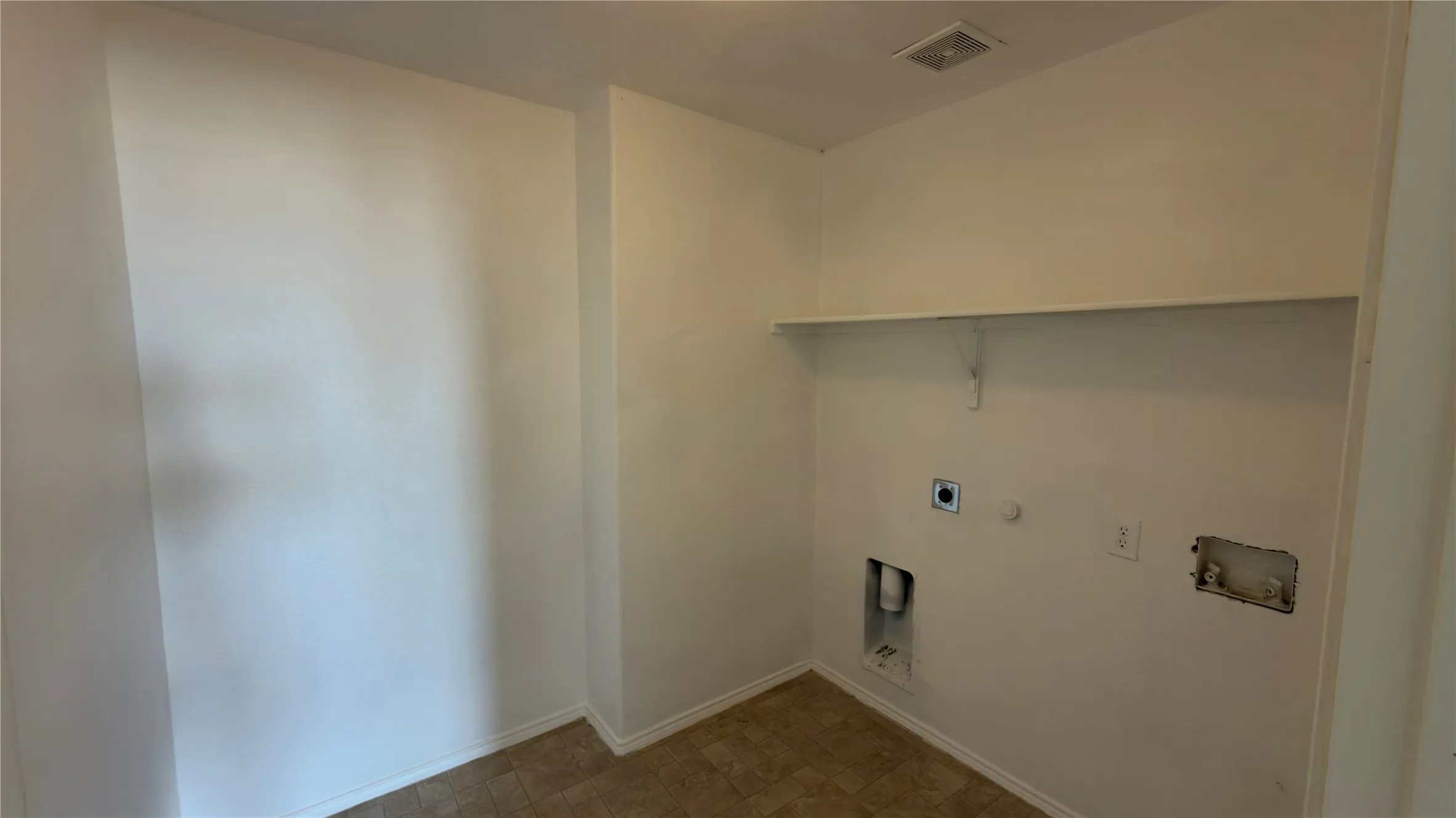 Laundry area with a built-in shelf and utility connections