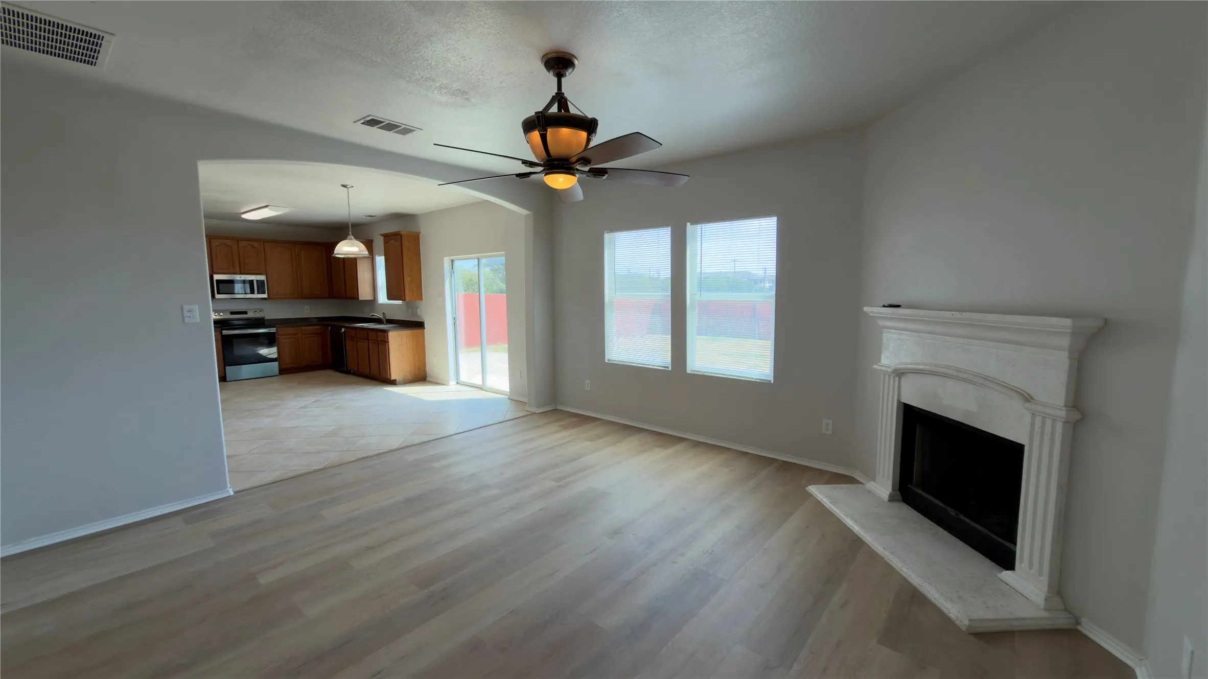 Living room featuring wood-finish flooring, a ceiling fan, and a fireplace with a mantel