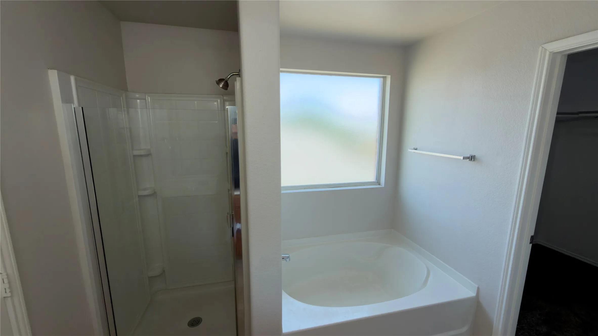 Enclosed shower with clear glass door, built-in bathtub, and frosted window