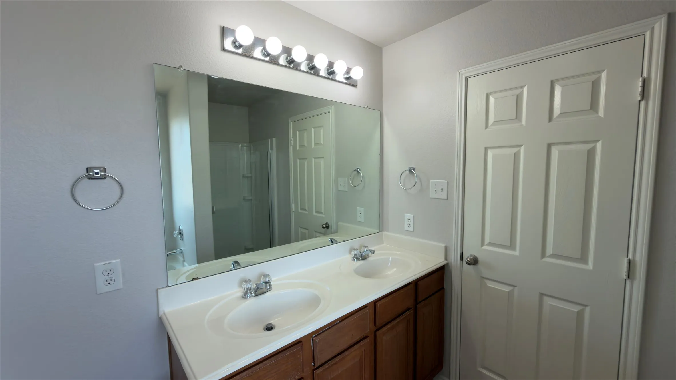 Dual vanity with integrated sinks, wood-finish cabinetry, and a full-width mirror