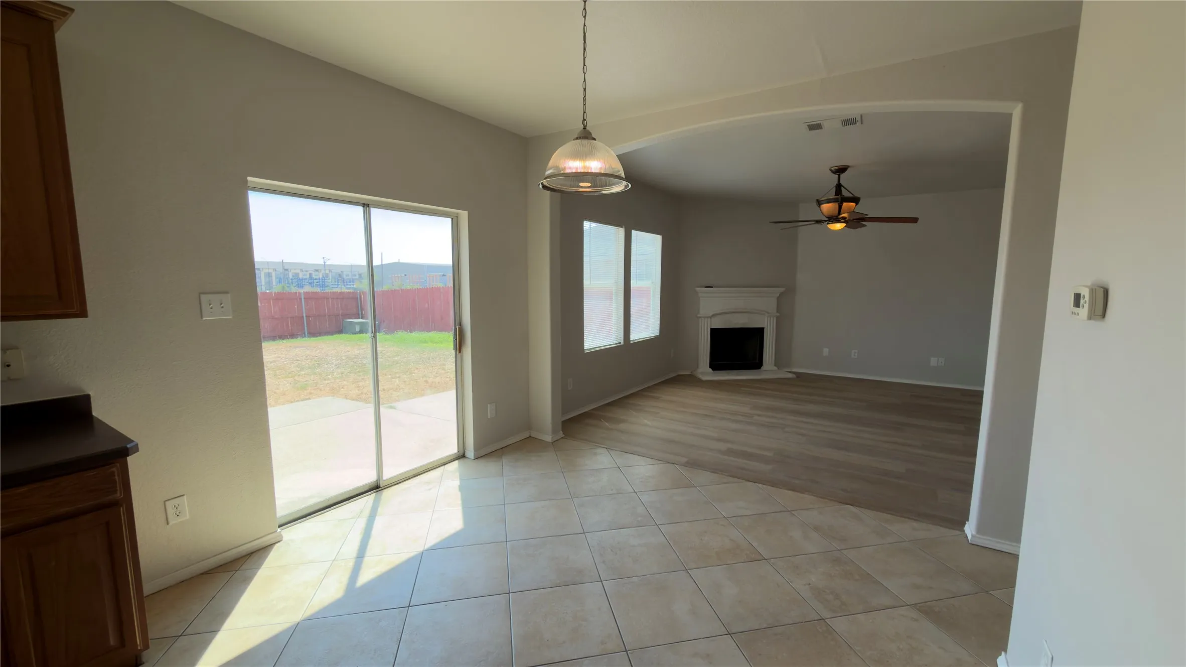 Tiled flooring, sliding glass patio door, arched doorway, engineered wood flooring, and ceiling fan with integrated lighting