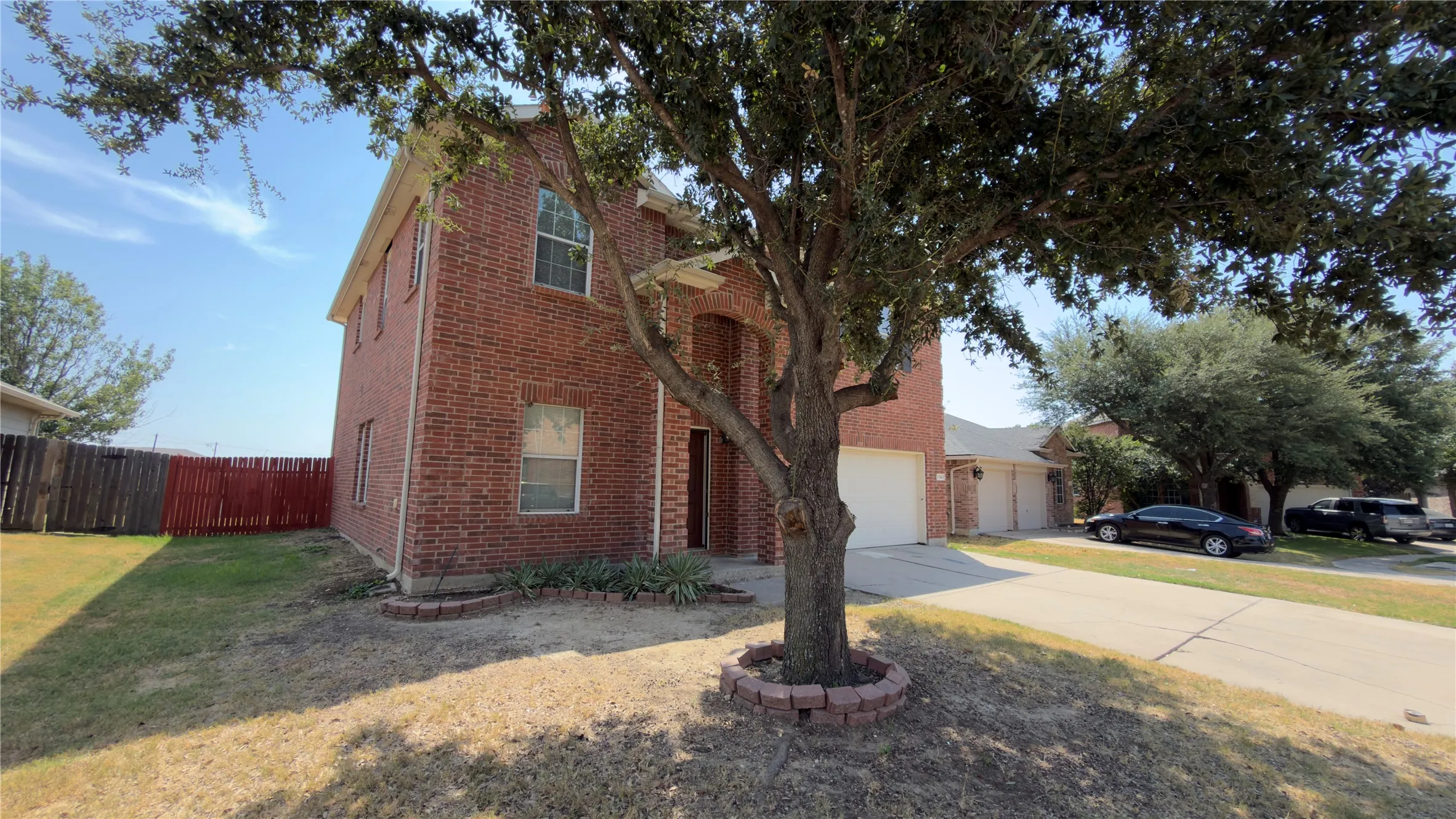 Two-story brick exterior with an arched entry, two-car garage, and established front landscaping