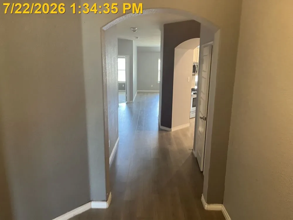 Archway entry with wood-finish flooring extending throughout