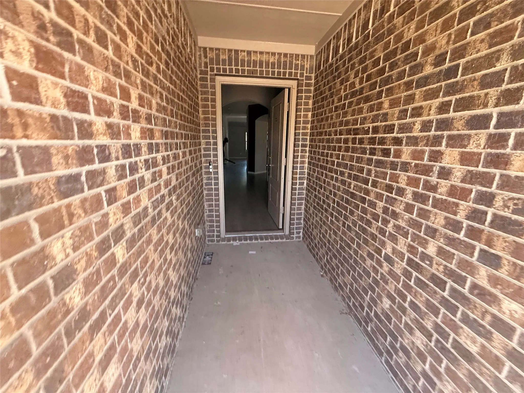 Brick exterior entry with covered porch and concrete flooring