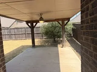 Covered patio with concrete flooring, wood posts, and an integrated ceiling light fixture
