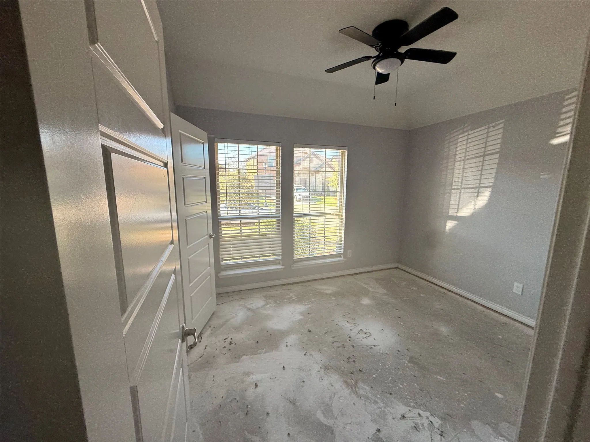 Room with two windows, a ceiling fan with integrated lighting, and a white paneled door