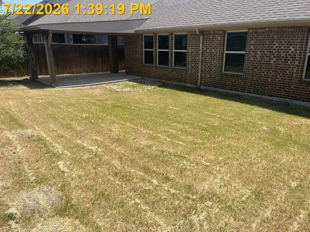Brick exterior with multiple windows, covered patio featuring a concrete slab, and a wood privacy fence