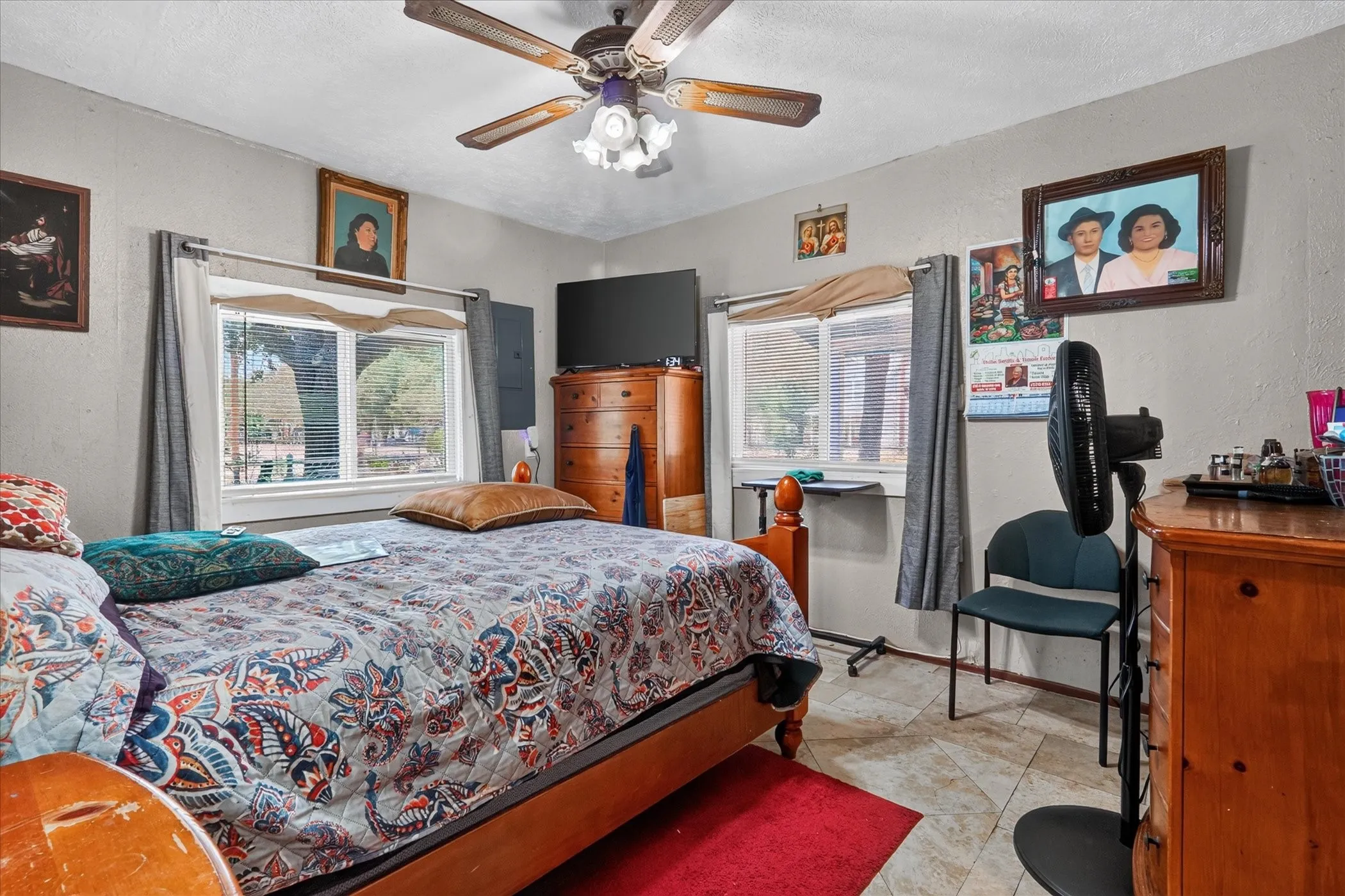 Ceiling fan with light fixture, two windows, and tile flooring